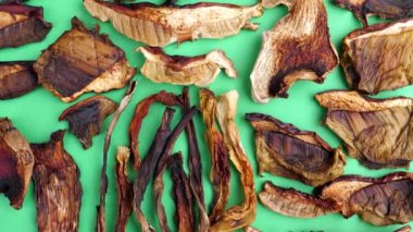 Kamera yavaş yavaş kurutulmuş boletus edulis, cep veya porcini mantar parçalarının üzerinde yeşil arkaplanda hareket ediyor..