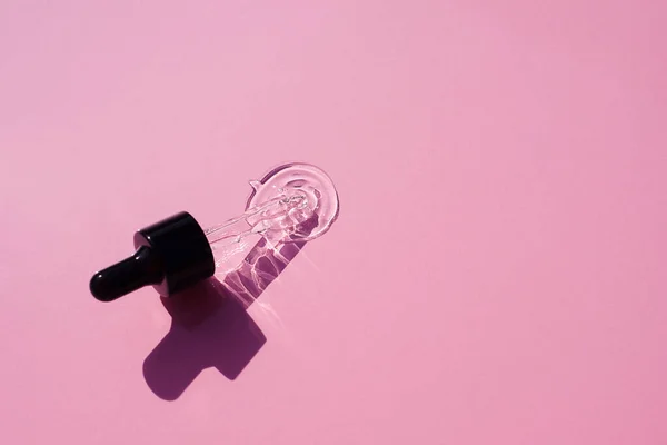 Otevřete víčko s kapátkem pipetou se sérem. Růžové pozadí s denním světlem a vzhled textury gelu. — Stock fotografie