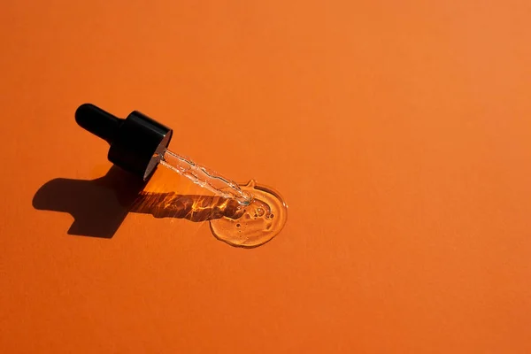 Otevřete víčko s kapátkem pipetou se sérem. Oranžové pozadí s denním světlem a vzhled textury gelu. — Stock fotografie