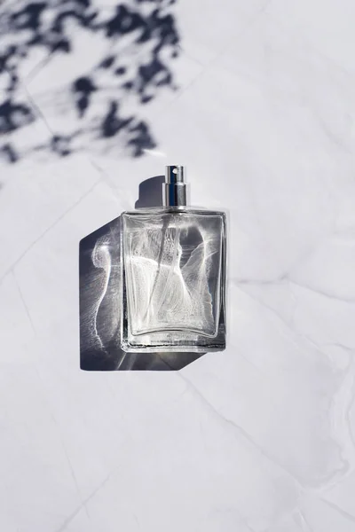 Transparent bottle of perfume with spray on white marble surface. Luxury presentation. — Stock Photo, Image
