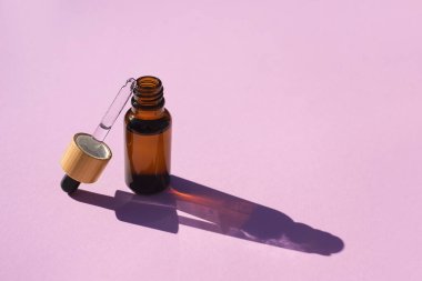 Şişeyi damlalık pipetle serumla ya da gerekli yağla açın. Gün ışığında pembe arkaplan.