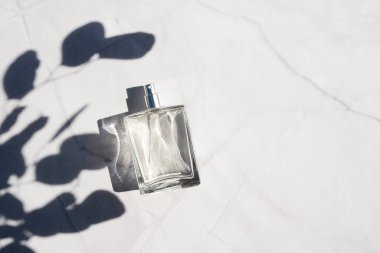 Beyaz mermer yüzeyine sprey sıkılmış saydam bir parfüm şişesi..