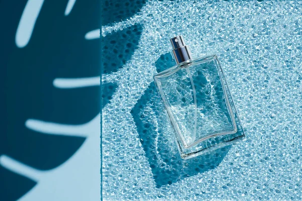 Transparente Flasche Parfüm auf blauem Hintergrund und Wellglas. — Stockfoto