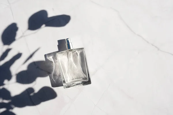 Transparent bottle of perfume with spray on white marble surface. — Stock Photo, Image