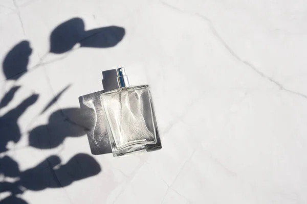 Frasco transparente de perfume con spray sobre superficie de mármol blanco. — Foto de Stock