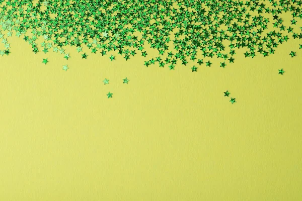 Confetti na forma de estrelas sobre fundo verde. Dia festivo pano de fundo. — Fotografia de Stock