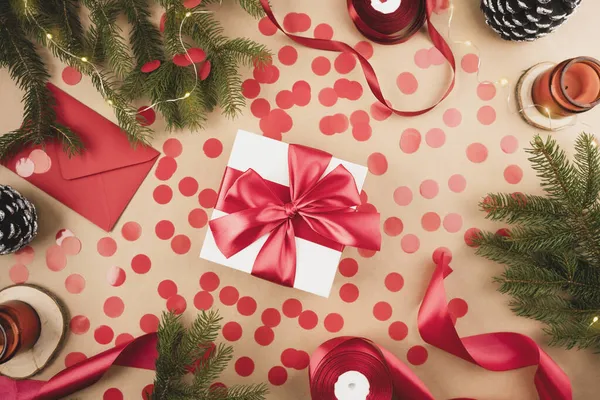 Біла подарункова коробка з червоною стрічкою з червоним конфетті на крафт-фоні . — стокове фото