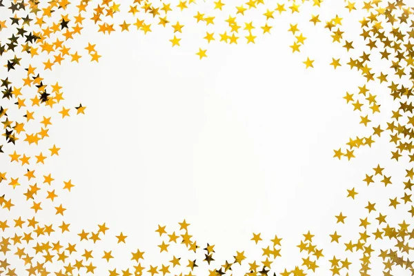 Confete dourado na forma de estrelas isoladas sobre fundo branco. Dia festivo pano de fundo. — Fotografia de Stock