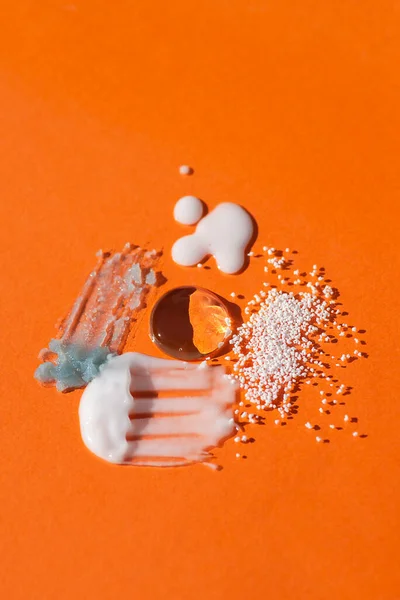 Cosmetic smears and drops. Appearance of the texture of the cream and oil on an orange background. — Stock Photo, Image