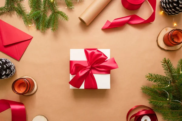 Confezione regalo bianca con nastro rosso su sfondo kraft. Imballaggio e preparazione dei regali per la celebrazione. — Foto Stock