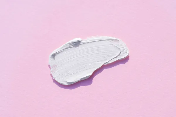 A smear of cream or face mask. The appearance of the texture of the cream on pink background.