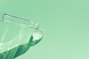 Pipette, açık yeşil arka planda yumuşak odak noktasında. Güneş ışığının güzel gölgesi. Cilt bakım ürünleri, doğal kozmetik ürünleri. Yüz ve vücut bakımı için güzellik konsepti