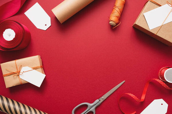 Крафт подарочные коробки с оранжевой нитью на красном фоне. Упаковка и подготовка подарков к празднованию.