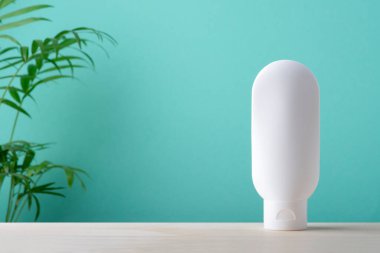 Krem veya losyon için plastik beyaz tüp. Nane yeşili ve yeşil palmiye yapraklı ahşap yüzey zeminli cilt konsepti. Yüz bakımı için spa doğal kozmetik konsepti
