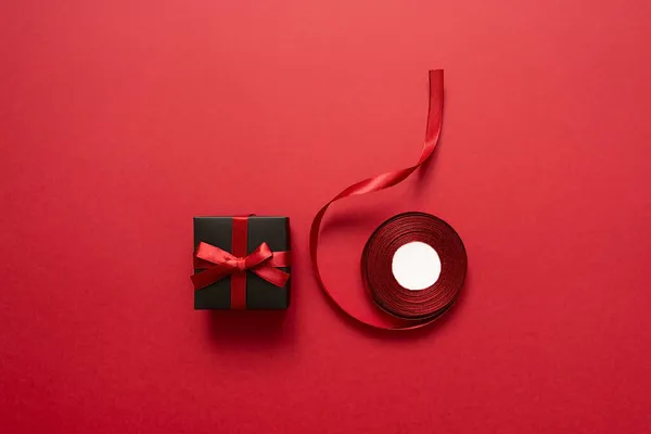 Μαύρο Δώρο Φιόγκο Και Κορδέλα Κόκκινο Φόντο Συσκευασία Και Προετοιμασία — Φωτογραφία Αρχείου