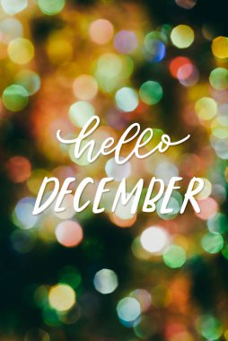 Elle çizilmiş Hello December renkli ışıkların güzel doğal bokeh üzerine. Yılbaşı kartı.