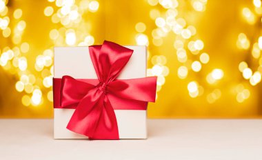 Bokeh ışıklarının arka planında kurdele olan beyaz hediye kutusu. Sevgililer Günü, Noel veya Yeni Yıl arkaplanı.