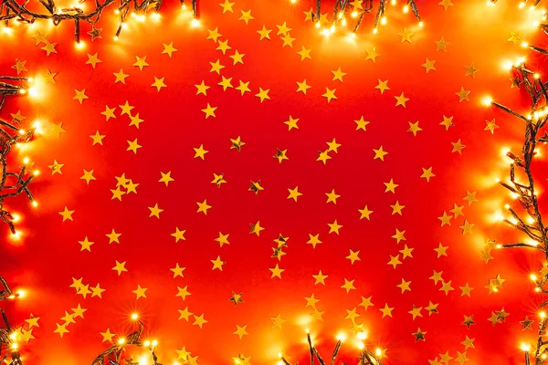 星の形で黄金のコンフェッティと赤の背景 バレンタイン クリスマス 新年の背景にライトが付いています ミニマルなデザインのフラットレイスタイル — ストック写真