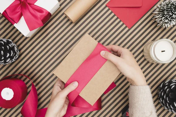 Young woman packing a gift box on striped background. Preparation of gifts for the celebration — Stock Photo, Image