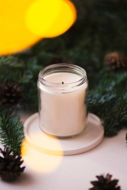 Yeşil Noel ağacı dallarının arka planında şeffaf kavanozda mum var. Aromalı ev konforu.