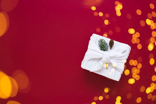 Біла подарункова коробка в тканині на червоному тлі. Різдвяний новорічний фон з обгорткою Фуросікі та боке-світлом . — стокове фото