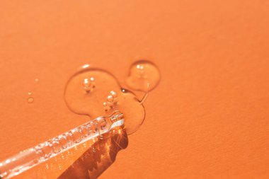 Pipette, yumuşak odak noktasında turuncu arka planda. Güneş ışığının güzel gölgesi. Cilt bakım ürünleri, doğal kozmetik ürünleri. Yüz ve vücut bakımı için güzellik konsepti