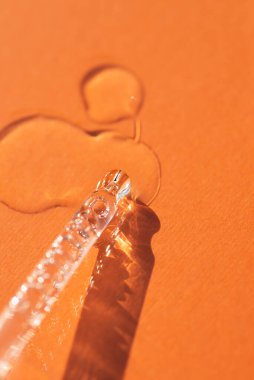 Pipette, yumuşak odak noktasında turuncu arka planda. Güneş ışığının güzel gölgesi. Cilt bakım ürünleri, doğal kozmetik ürünleri. Yüz ve vücut bakımı için güzellik konsepti