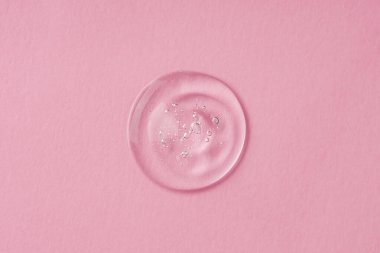 Şeffaf kozmetik ürün serumu jeli damlası. Pembe arka planda köpüklü sıvı dokusu. Cilt bakım ürünleri, doğal kozmetik ürünleri. Yüz ve vücut bakımı için güzellik konsepti
