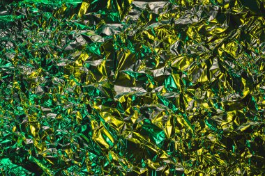 Yeşil ve sarı alüminyum kırışık folyo arka plan. Yaratıcı eğilimi yansıtan soyut parlak doku. Açık neon fütüristik renkler. Ekranlar, web sitesi, el ilanları ve broşürler için renkli parlayan arkaplan