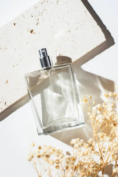 製品のプレゼンテーションと白の背景のための香水とピンク大理石プレートの透明なボトル 夏時間と乾燥植物の香りのプレゼンテーション 女性と男性の本質 — ストック写真