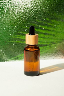 Kehribar cam şişesinde damlatan pipette serum ya da kıvrımlı camların arka planında gerekli yağ var. Palmiye yapraklı cilt bakımı. Yüz bakımı için güzellik konsepti