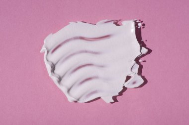 Krem lekesi ya da yüz maskesi. Kremin pembe arka plandaki dokusunun görünümü. Cilt bakım ürünleri, doğal kozmetik ürünleri. Yüz ve vücut bakımı için güzellik konsepti