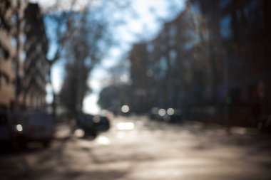 Odaklanmamış yol kenarı. Eski şehir manzaralı doğal bir bokeh, odak arkaplanı bulanık. Mesaj veya reklam için soyut ve güzel bir arkaplan. Odaklanmamış şehir manzarası, evleri ve arabaları olan cadde