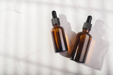 Damla pipetli Amber cam şişeleri ya da beyaz arka planda gerekli yağ. Güzel gölgeli cilt makyajı. Yüz bakımı için güzellik konsepti. Metin için yer