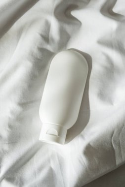Krem için plastik beyaz tüp ya da hafif kumaş arka planında losyon. Güneş ışığı ve güzel gölgeli cilt bakım kozmetik sunumu. Yüz bakımı için güzellik konsepti.