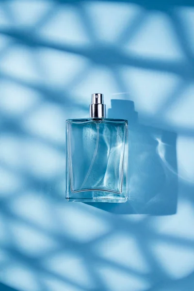 蓝色背景的透明香水瓶 光天化日下的芬芳呈现潮流的概念与美丽的影子 妇女的本质 — 图库照片