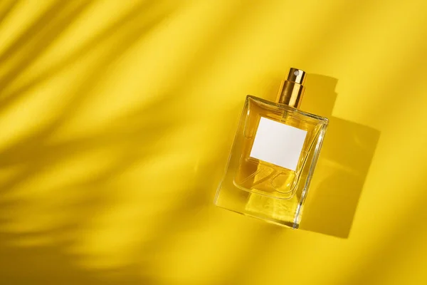 Przezroczysta Butelka Perfum Etykietą Żółtym Tle Prezentacja Zapachu Przy Świetle — Zdjęcie stockowe