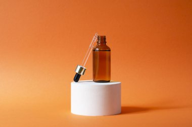 Şişeyi damlalık pipetle serumla ya da gerekli yağla açın. Turuncu arka plan ve gün ışığı. Cilt bakım ürünleri, doğal kozmetik ürünleri. Yüz ve vücut bakımı için güzellik konsepti