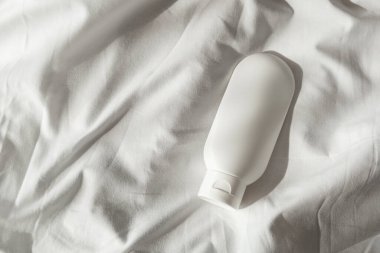 Krem için plastik beyaz tüp ya da hafif kumaş arka planında losyon. Güneş ışığı ve güzel gölgeli cilt bakım kozmetik sunumu. Yüz bakımı için güzellik konsepti.