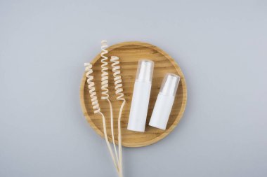 Krema için pompalı iki plastik beyaz şişe ya da gri arka plandaki ahşap podyumda losyon. Gri arkaplandaki üst görünüm. Cilt kozmetiği. Yüz bakımı için güzellik konsepti