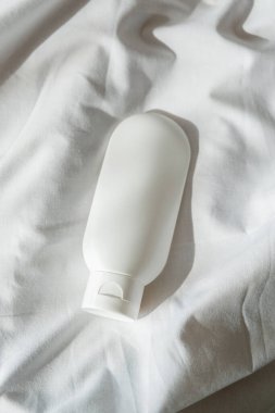 Krem için plastik beyaz tüp ya da hafif kumaş arka planında losyon. Güneş ışığı ve güzel gölgeli cilt bakım kozmetik sunumu. Yüz bakımı için güzellik konsepti.