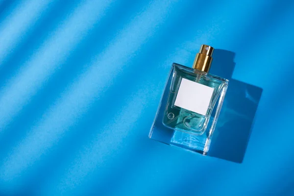 Transparentní Lahvička Parfému Etiketou Modrém Pozadí Prezentace Vůně Denním Světlem — Stock fotografie
