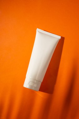 Krema için plastik beyaz şişe ya da turuncu arka planda losyon. Güzel palmiye gölgeli cilt kozmetiği. Yüz bakımı için güzellik konsepti.