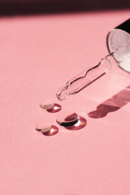 Serum düşüşlü yakın çekim damlası olan kapağı aç. Pembe arka plan, gün ışığı ve jel dokusunun görünüşü. Cilt bakım ürünleri. Yüz ve vücut bakımı için güzellik konsepti
