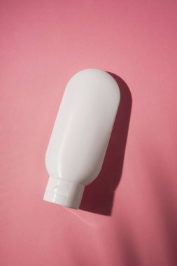 Krem veya losyon için plastik beyaz tüp. Cilt bakımı ya da güzel gölgeli pembe arka planda güneş kremi. Yüz bakımı için güzellik konsepti