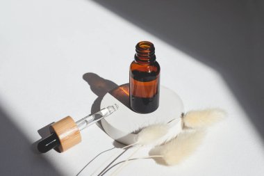 Bambu kapaklı kehribar cam düşürücü şişeler. Ürün sunumu için beyaz beton podyuma odaklı serumlu ya da temel yağlı pipeti aç. Cilt kozmetiği. Güzellik konsepti