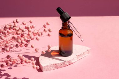 Siyah kapaklı kehribar cam damlaları. Serumlu boru ya da ürün sunumu için beyaz beton podyuma yumuşak odaklı gerekli yağ. Kırmızı çiçekli cilt makyajı. Güzellik konsepti