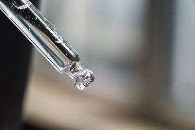 Pipette 'in serumu ya da bulanık arka planda kozmetik sıvısı var. Jel dokusunun görünüşü. Cilt bakım ürünleri. Yüz ve vücut bakımı için güzellik konsepti