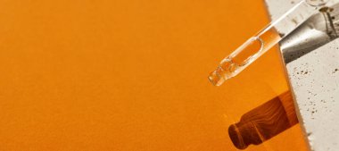 Pipette serumla ya da kozmetik sıvıyla yakın plan sarı arka plan yumuşak odaklı. Güneş ışığının güzel gölgesi. Cilt bakım ürünleri, doğal kozmetik ürünleri. Yüz ve vücut bakımı için güzellik konsepti