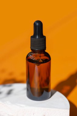 Kehribar şişesinde damla pipeti ve serum ya da gerekli yağ. Turuncu arka plan, gün ışığı ve güzel gölgeler. Cilt bakım ürünleri, doğal kozmetik ürünleri. Yüz ve vücut bakımı için güzellik konsepti